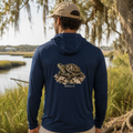 Man wearing a navy hoodie with a turtle graphic and 'Bluffton, SC' text, standing in a natural setting.