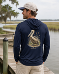 Man wearing a navy hoodie with a pelican design by a waterfront