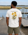 Man wearing a white t-shirt with a floral design by a lake