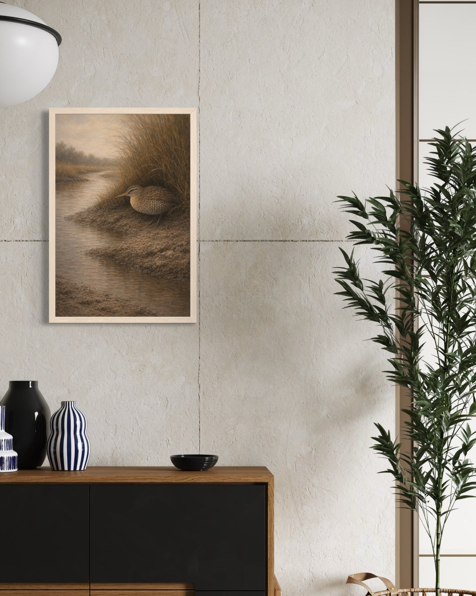 Framed artwork on a wall with a vase and plant in the foreground