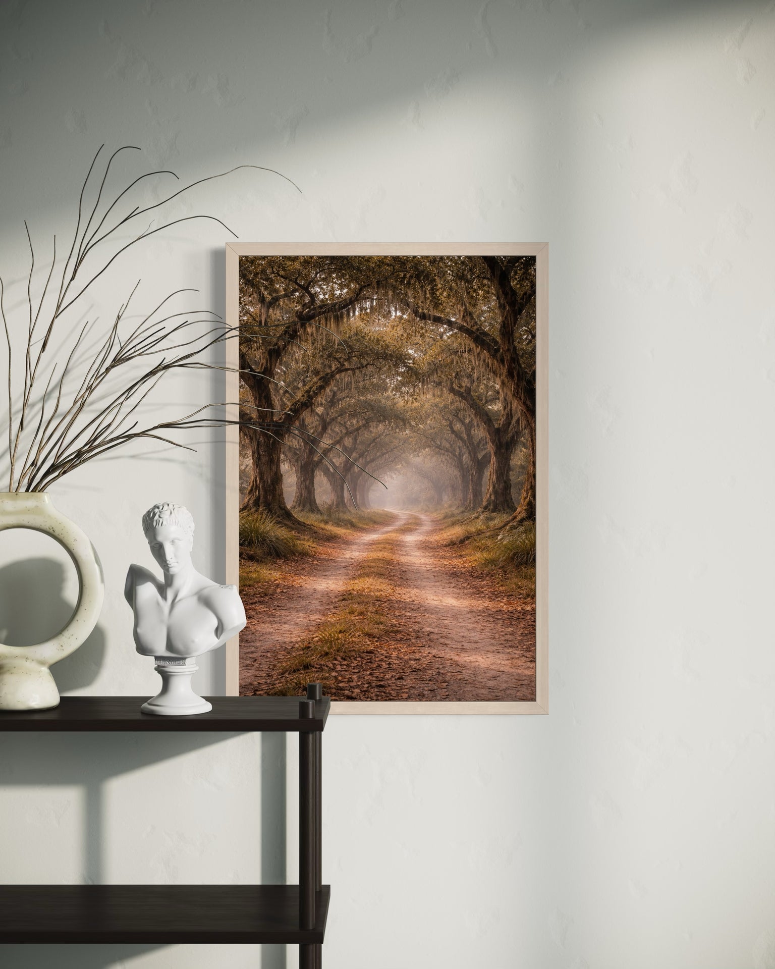 Framed artwork of a forest path on a wall next to decorative items.