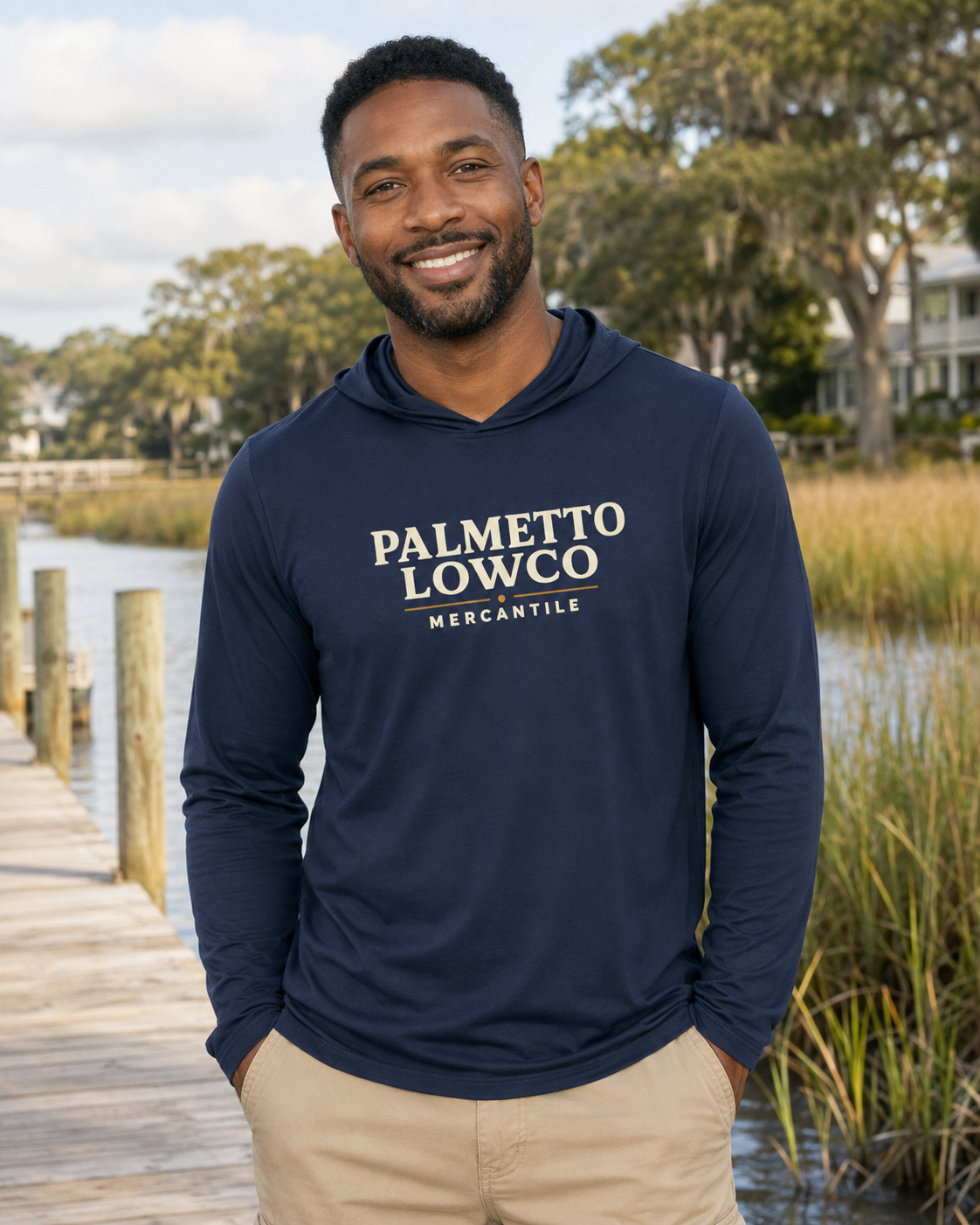 Man wearing a navy hoodie with 'Palmetto Lowco Mercantile' text, standing by a waterfront.