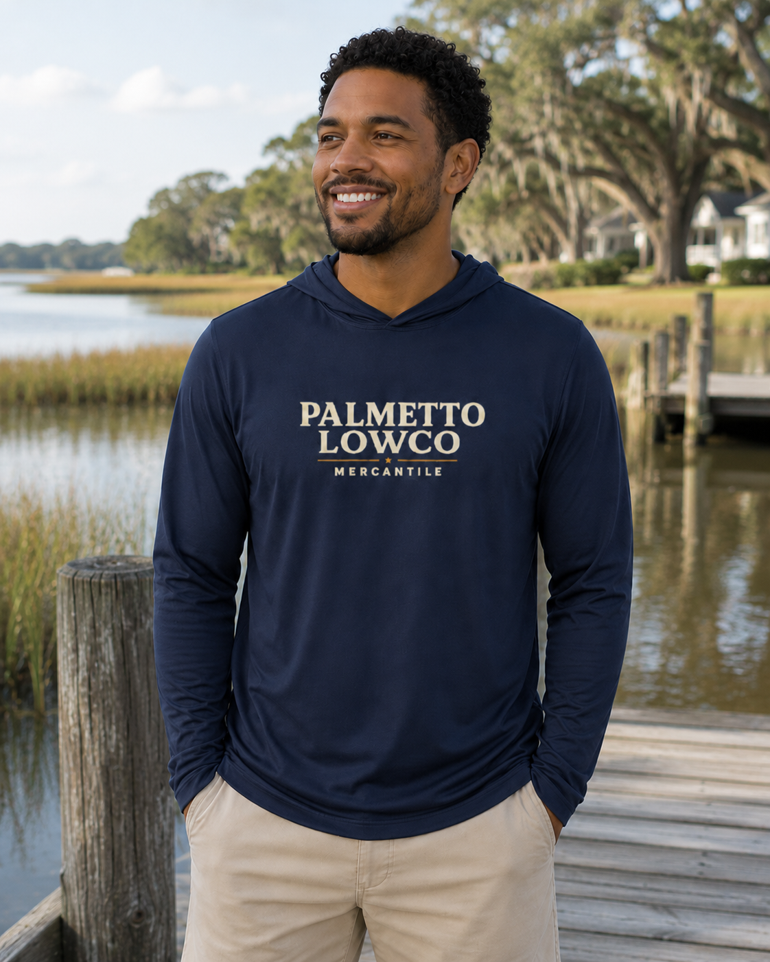Man wearing a navy hoodie with 'Palmetto Lowco Mercantile' logo by a waterfront.