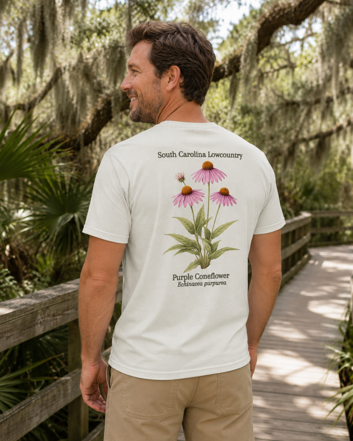 Man wearing a white t-shirt with a purple coneflower design in a natural setting