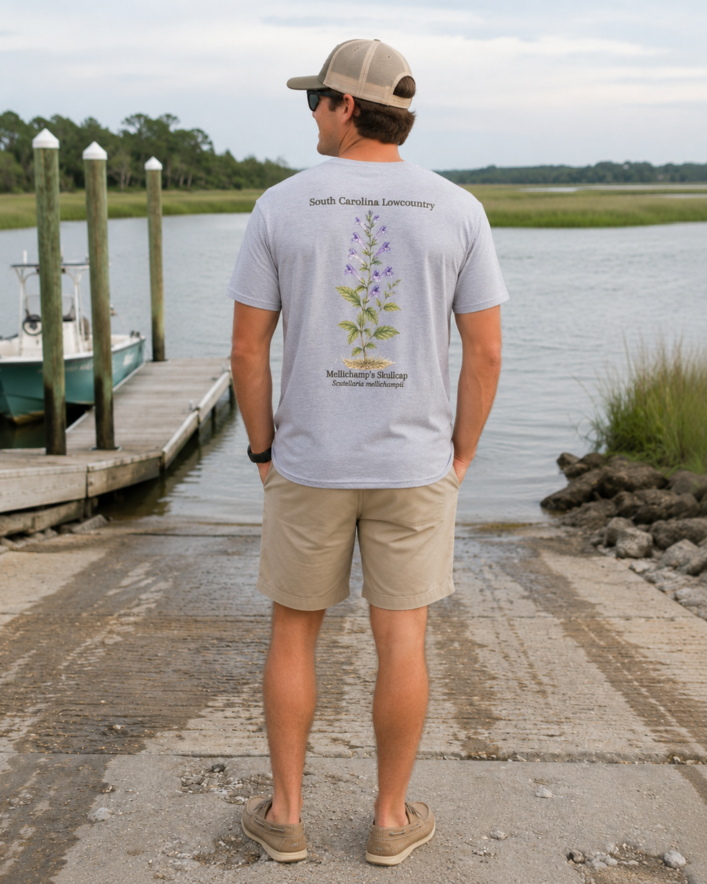 Man wearing a gray t-shirt with a plant design by a dock