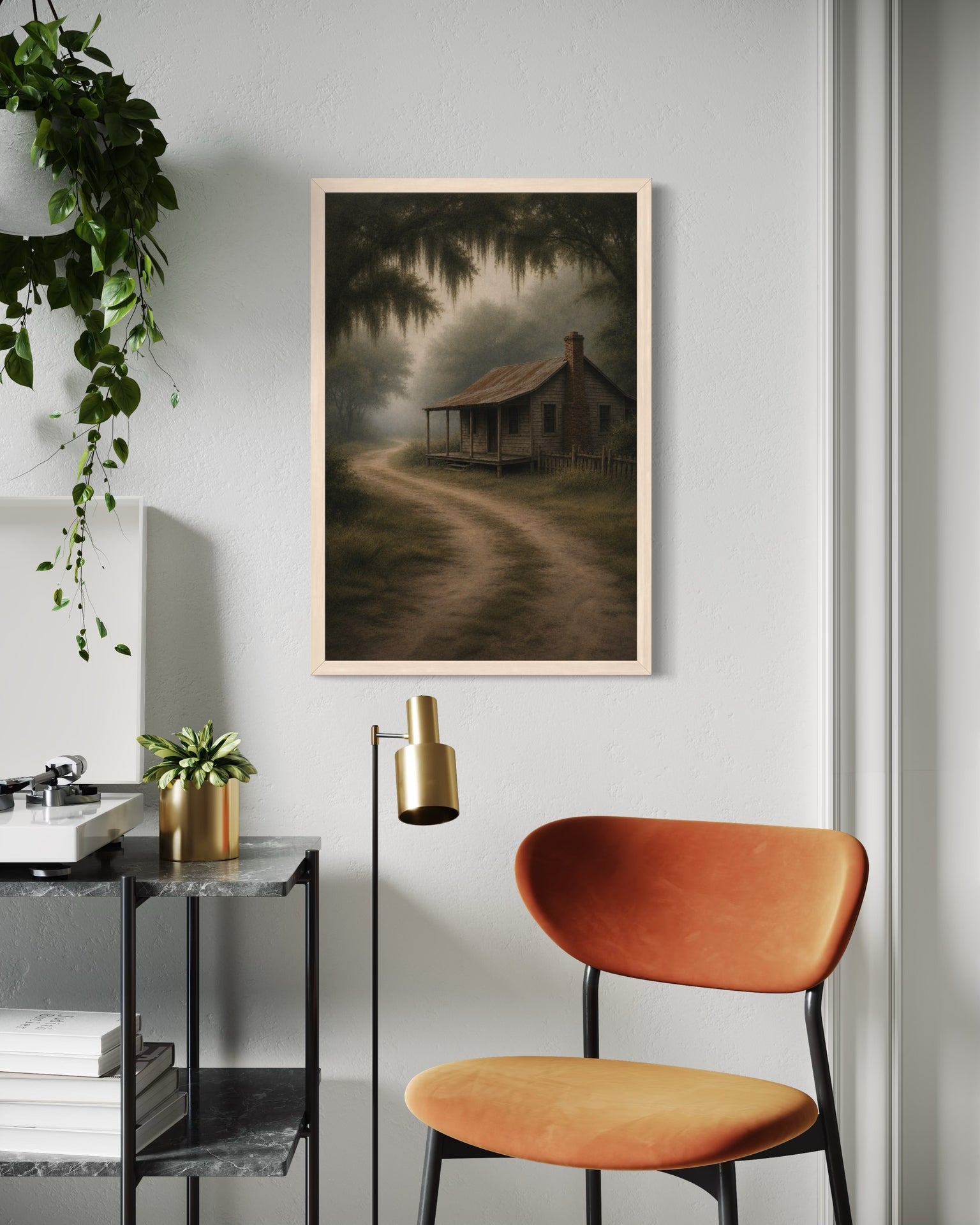 Framed artwork of a misty landscape on a wall above an orange chair and side table.