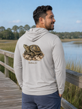 Man wearing a hoodie with a turtle graphic and text, standing by a lake.
